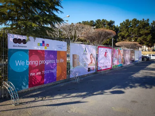 Row of cosmetics advertising banners on a metal fence outdoors
