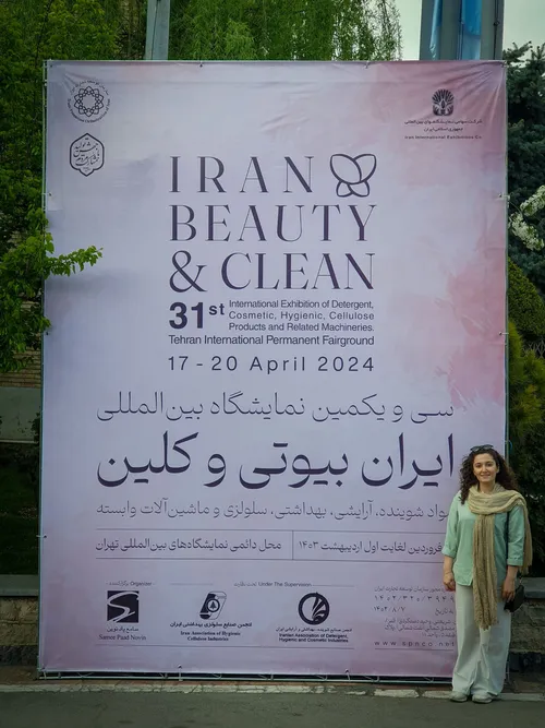 Woman standing beside Iran Beauty & Clean 2024 exhibition banner in Tehran