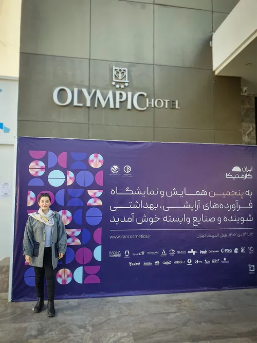 Woman standing before the exhibition welcome banner beneath Olympic Hotel sign