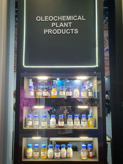 Lit display case of oleochemical plant product sample bottles on shelves