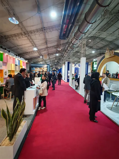 Crowded exhibition aisle with red carpet and brand booths
