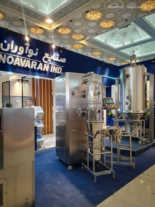 Noavaran Industries booth showing tall stainless processing vessels under ornate ceiling