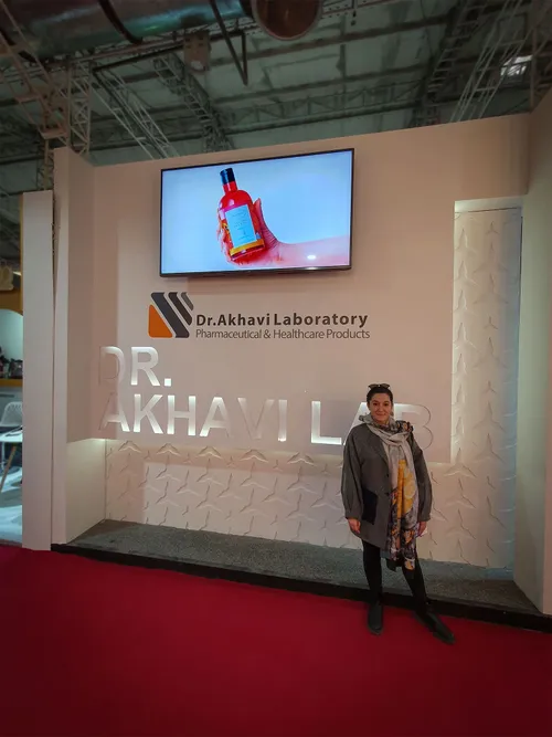 Woman standing before Dr. Akhavi Laboratory booth wall and screen