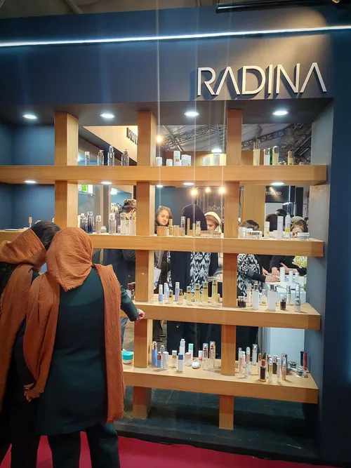 Two visitors viewing skincare bottles on a Radina display shelf