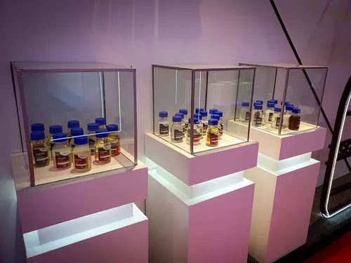Three glass cases on pink plinths holding rows of sample bottles
