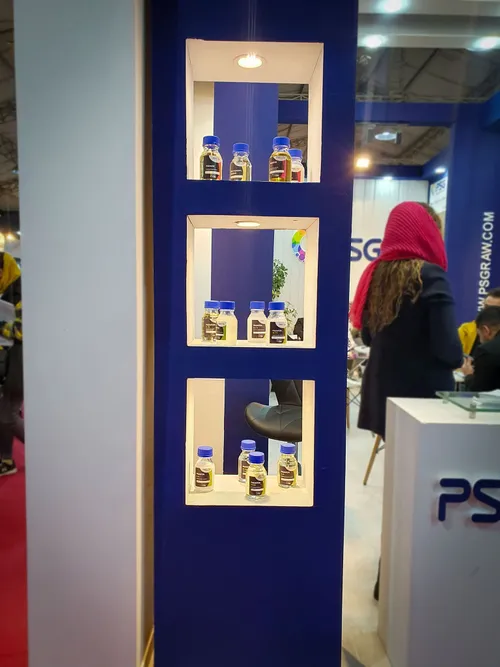 Blue niche shelves displaying small ingredient sample bottles at PSG booth