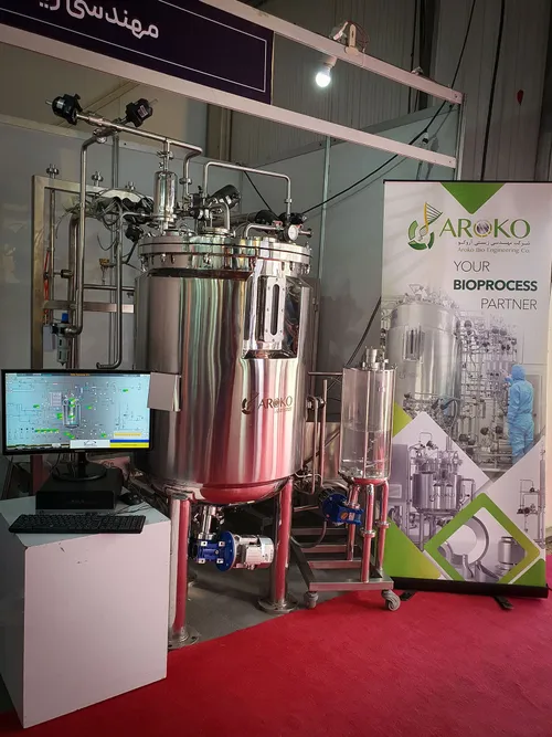 Stainless steel bioreactor with monitor beside an Aroko bioprocess banner