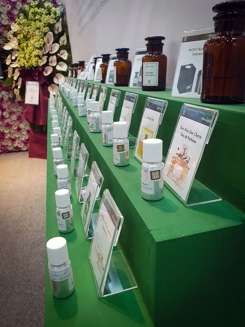 Rows of small fragrance sample bottles with labels on a green table